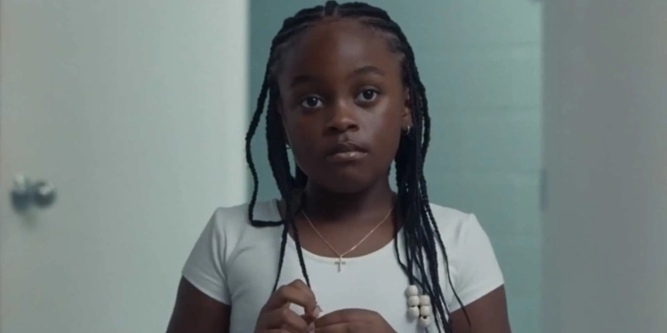 Gambar dari film On a Sunday at Eleven, tampak seorang anak berkulit hitam mengenakan kaos putih.